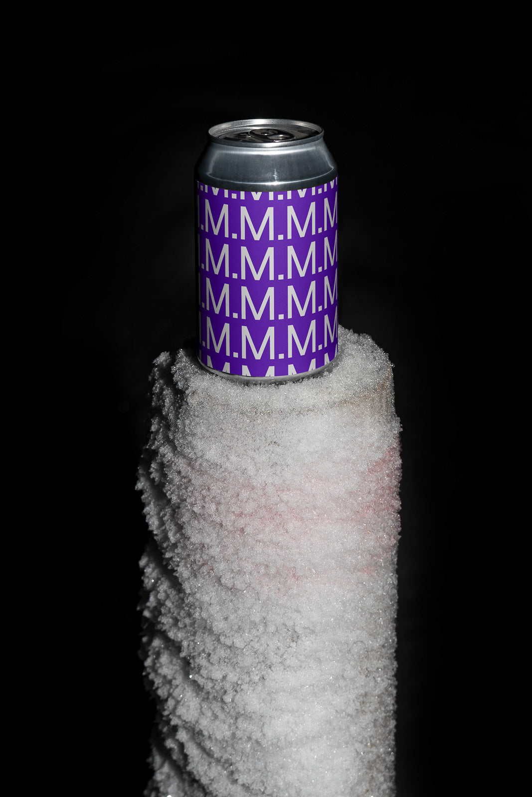 PSD mockup of a can with purple "M.M.M." pattern, placed on a snow-covered post against a dark background.