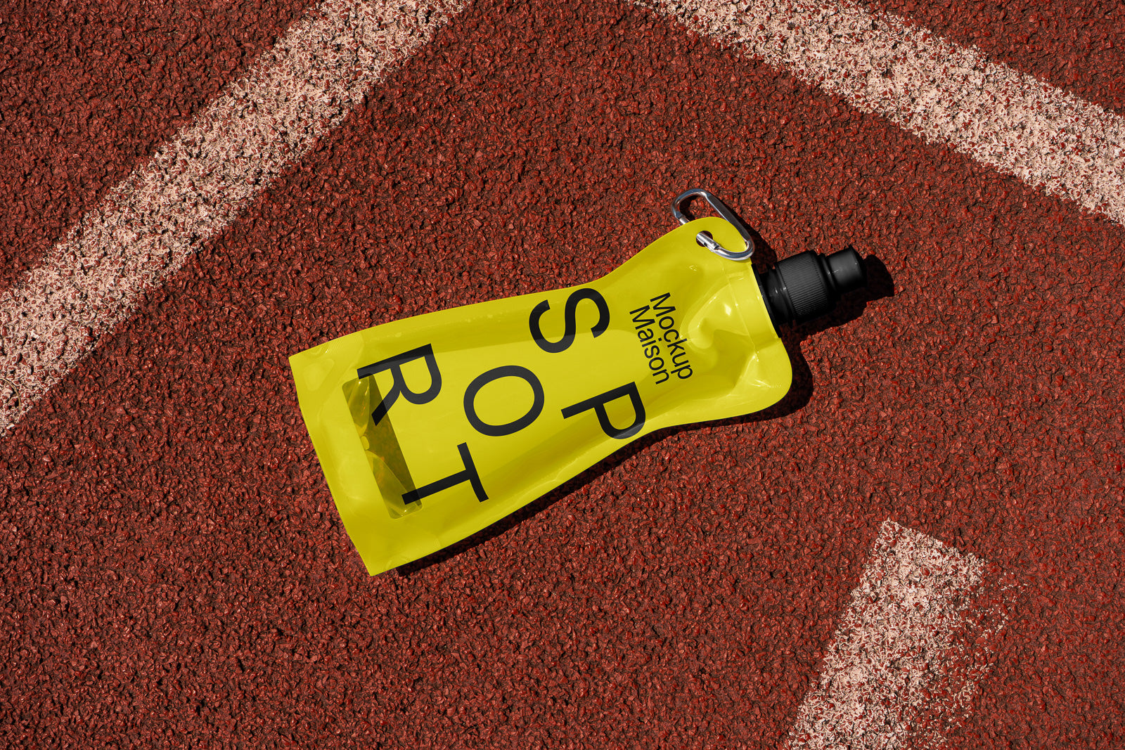 PSD mockup of a yellow sports pouch with a black cap and carabiner, lying on a red running track with white lane markings.