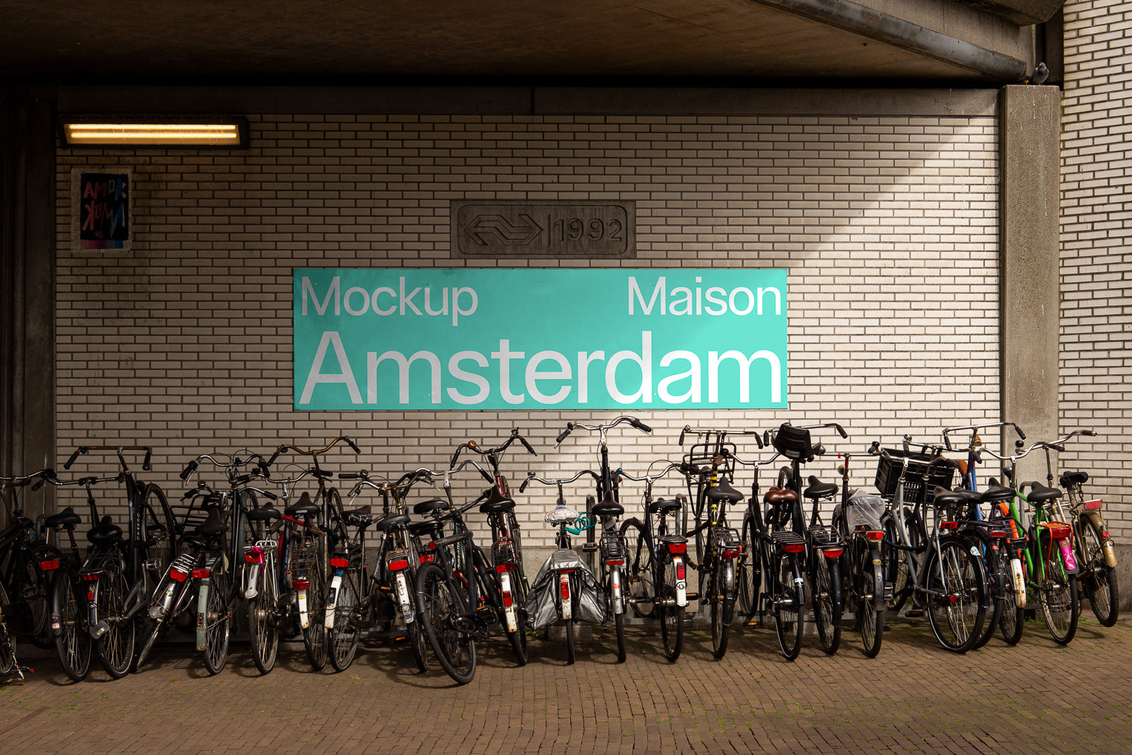 PSD mockup of a brick wall with a sign reading "Mockup Maison Amsterdam" in turquoise and white, above a row of parked bicycles.
