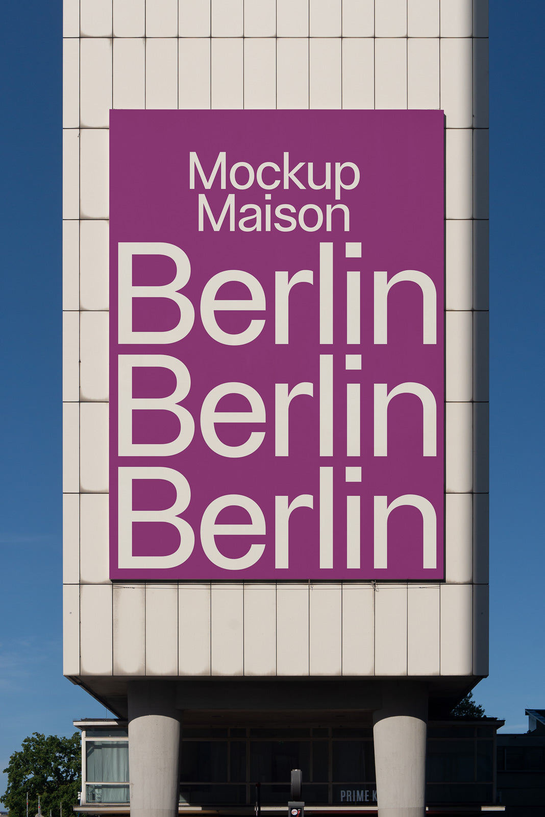 PSD mockup of a large vertical white wall featuring a purple sign with repeated text "Berlin" in bold white letters, captured against a clear blue sky.