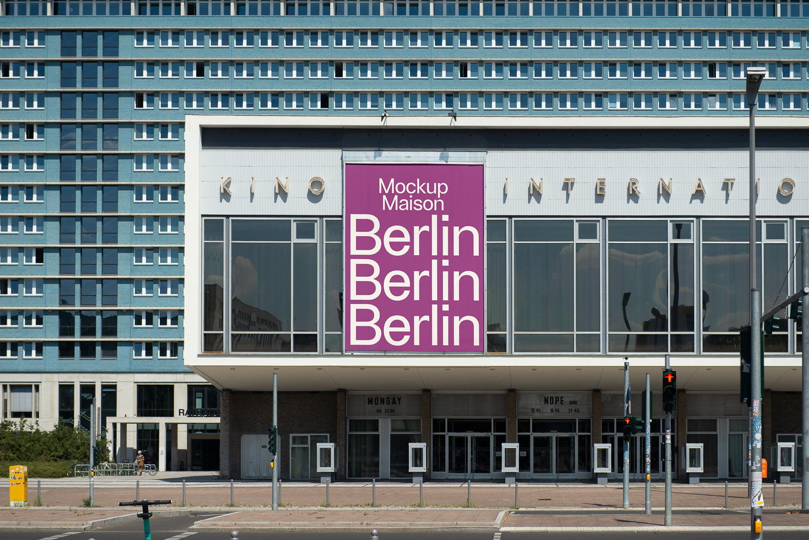PSD mockup of large pink banner displayed on glass-fronted building, featuring text "Berlin" repeatedly. Surroundings include street view and traffic lights.
