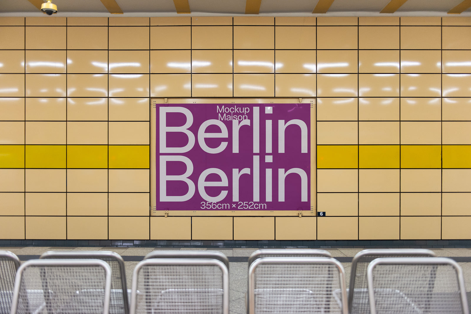 PSD mockup of a Berlin subway station wall with a large purple poster displaying "Berlin" in bold white letters, set against tan and yellow tiles.