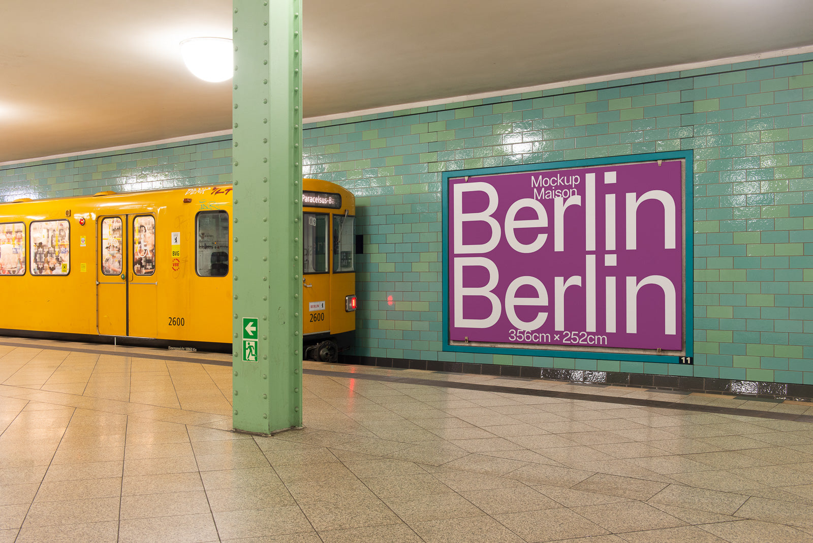 PSD mockup of a Berlin subway platform with a yellow train and a large purple Berlin-themed advertisement on a tiled wall.