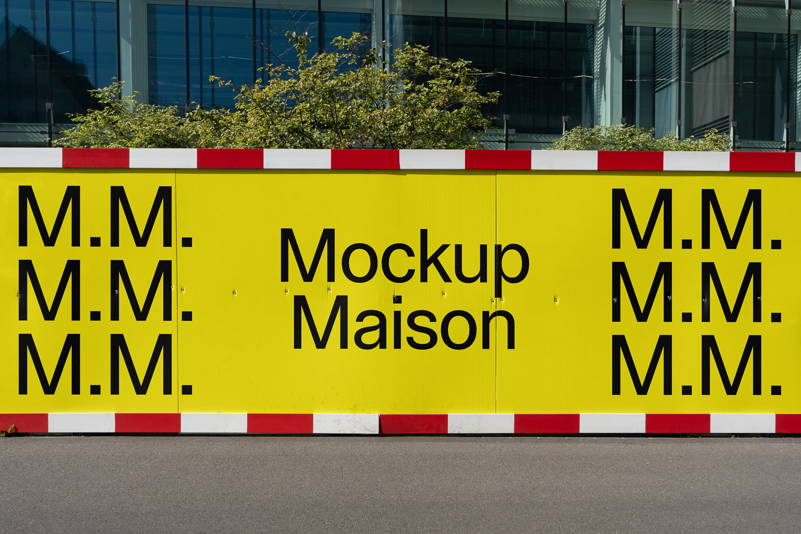 PSD mockup of a large yellow construction sign displaying the text "Mockup Maison" and repeated "M.M." lettering, set against an urban backdrop.