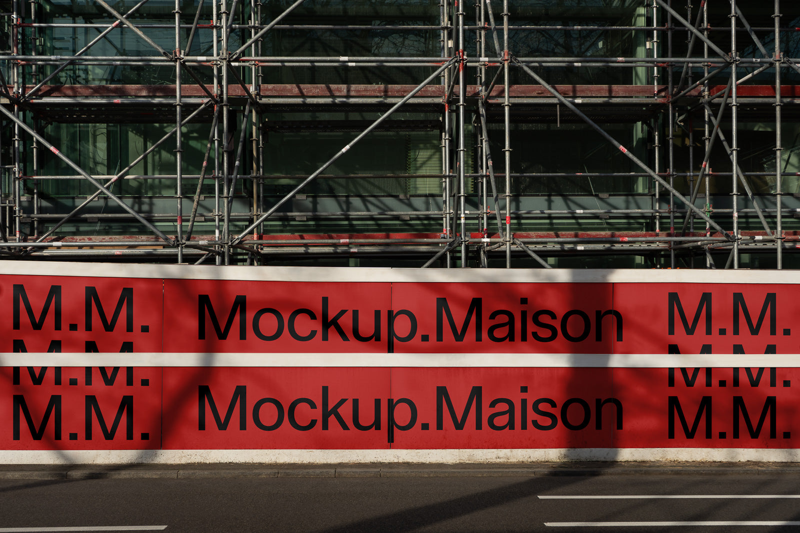 PSD mockup of a red construction barrier with "Mockup.Maison" and "M.M." text, set against a backdrop of building scaffolding.