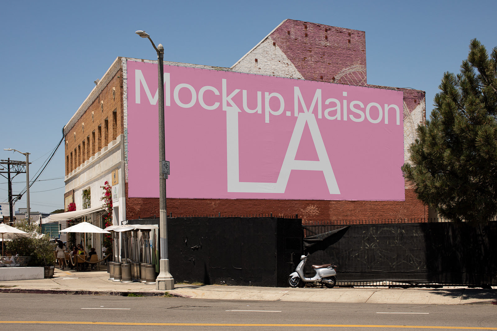 PSD mockup of a large pink billboard featuring white text on a brick building street corner, with a scooter parked beside a black fence.