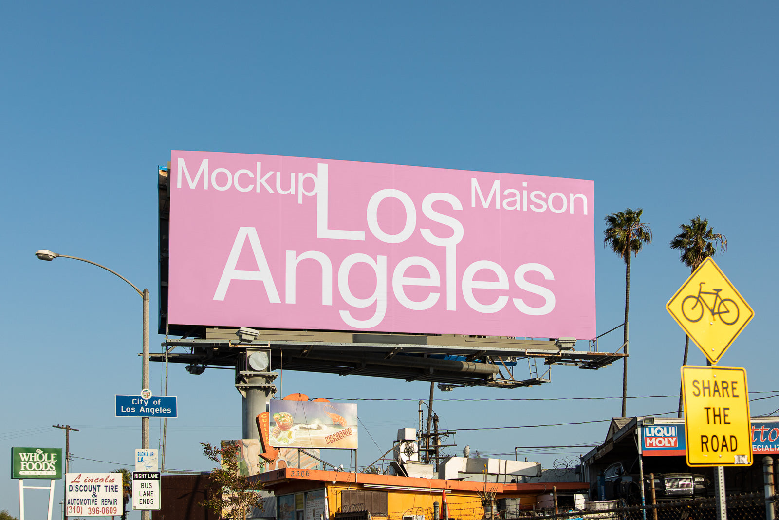 PSD mockup of a large pink billboard in Los Angeles displaying text, surrounded by city signs and palm trees under a clear blue sky.