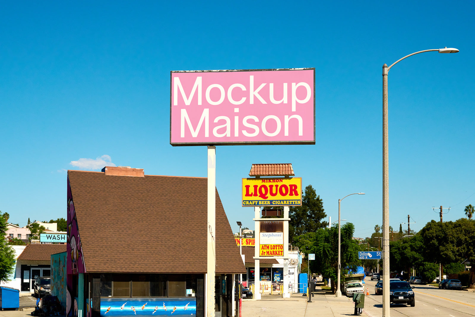 PSD mockup of a street scene featuring a large pink billboard with the text "Mockup Maison" against a clear blue sky, near shops and a liquor store.
