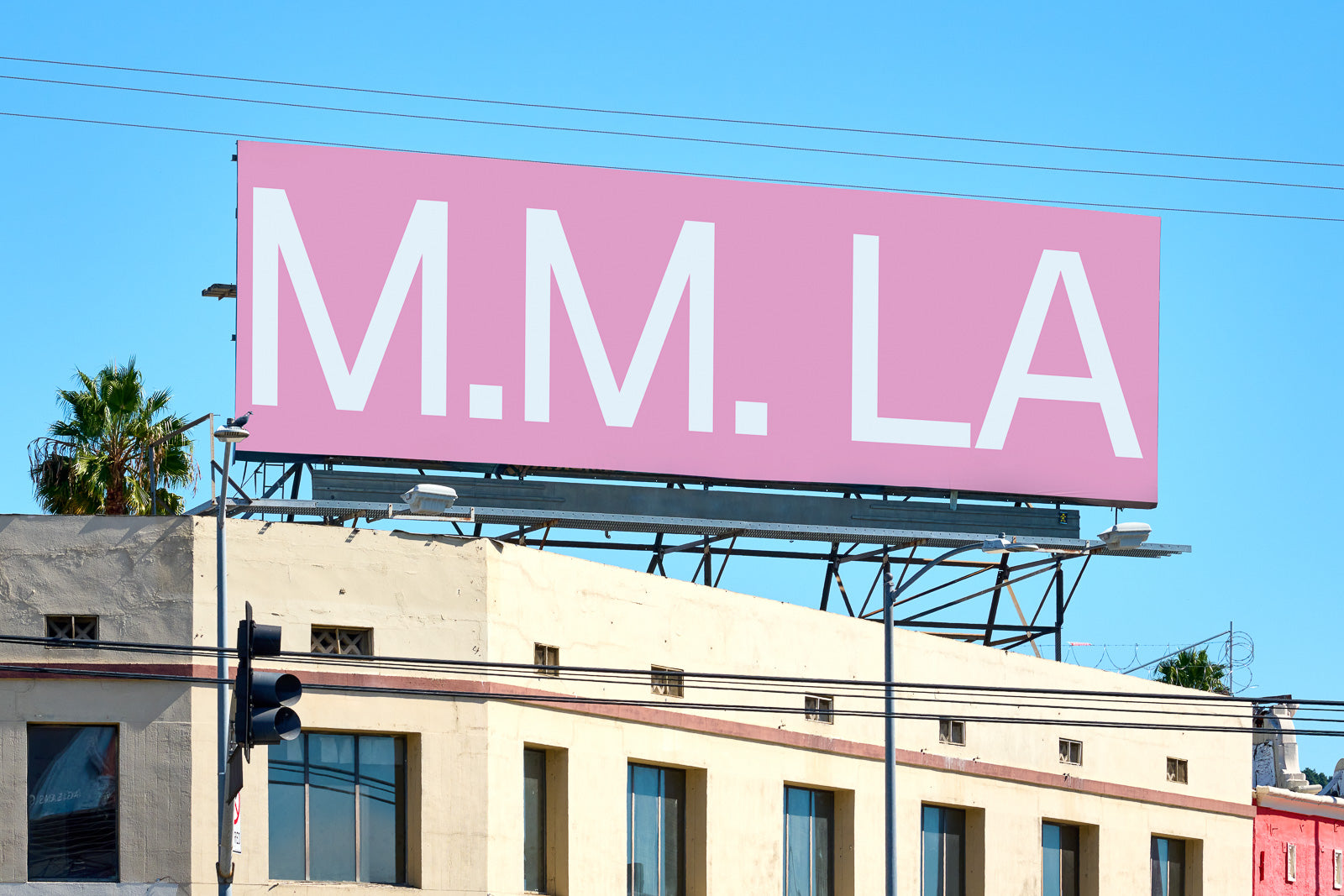 PSD mockup of a large pink billboard with white text "M.M. LA" mounted on a rooftop, against a clear blue sky backdrop.