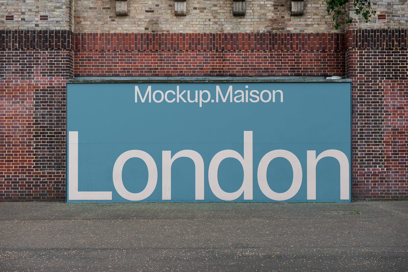 PSD mockup of a large blue street sign on a brick wall with "Mockup.Maison" at the top and "London" in bold white letters below.