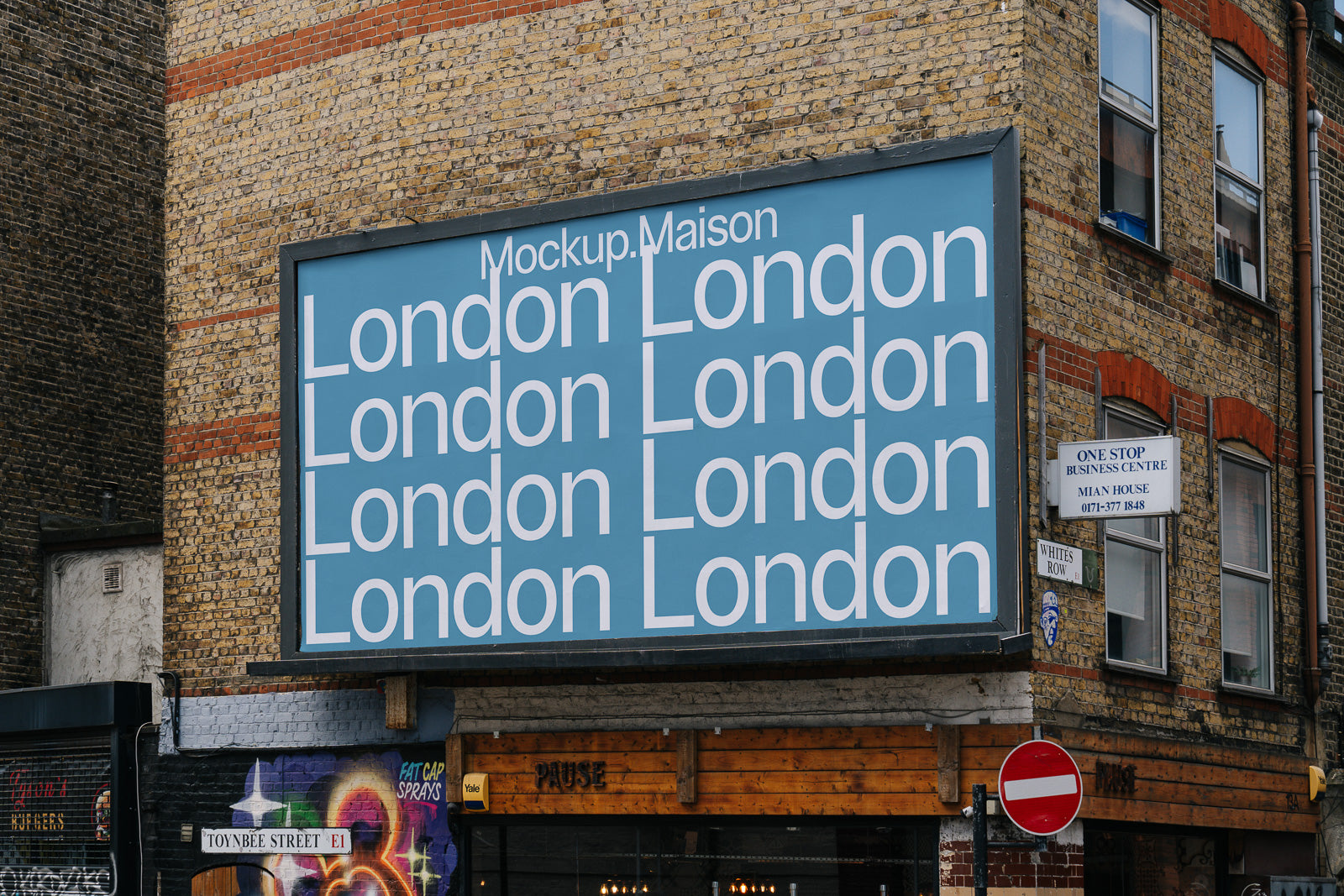 PSD mockup of a billboard on a brick building displaying the word 'London' repeatedly on a blue background, seen on an urban street corner.