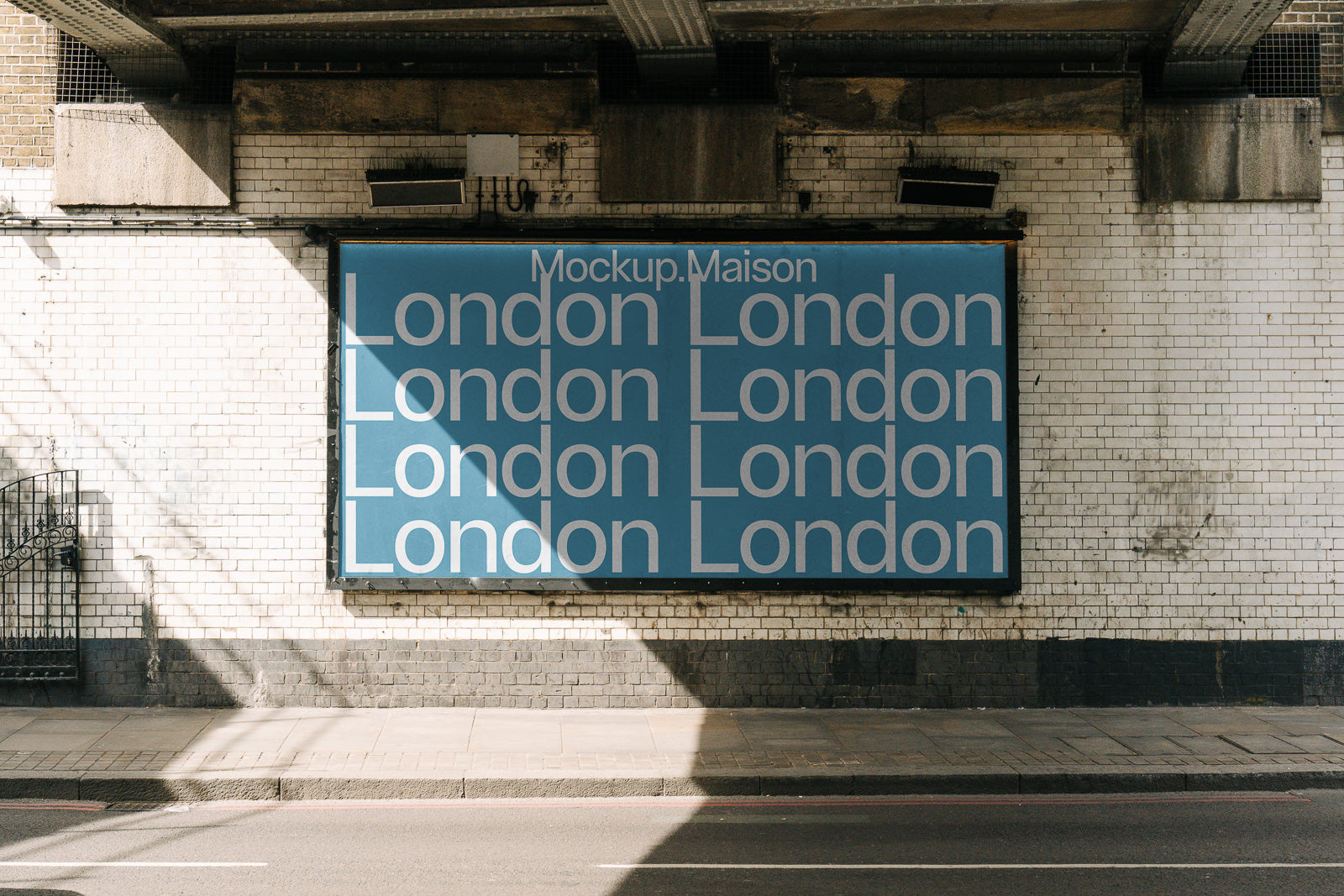 PSD mockup of a large blue billboard under an urban bridge, displaying the repeated word "London" in white text against a weathered brick wall.
