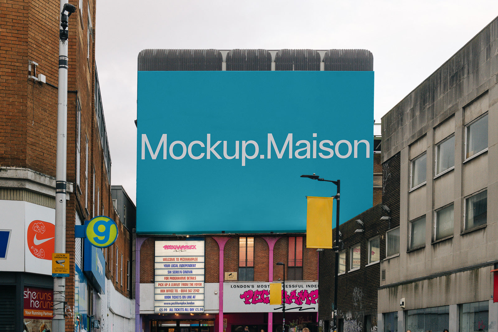 PSD mockup of a large blue billboard on an urban street. The billboard displays the text "Mockup.Maison," surrounded by buildings and street details.
