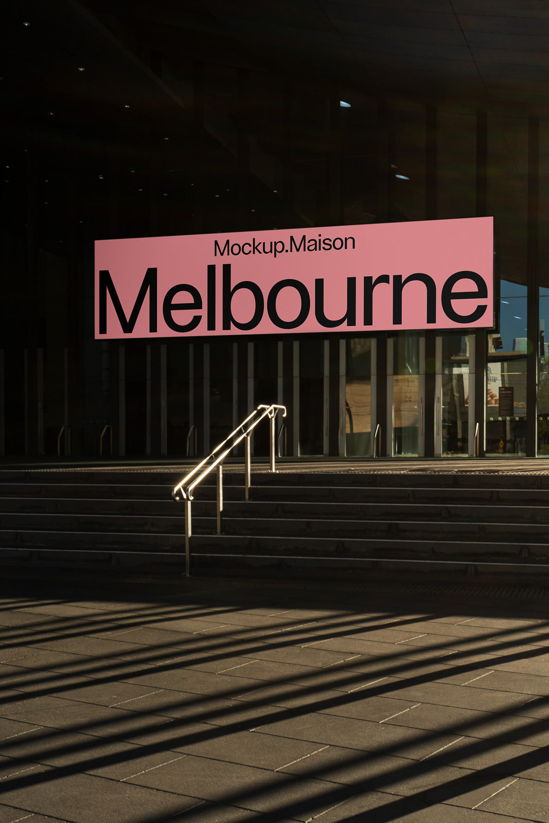 PSD mockup of an exterior sign with a pink background displaying the word "Melbourne" in bold, situated near steps and a railing in low sunlight.