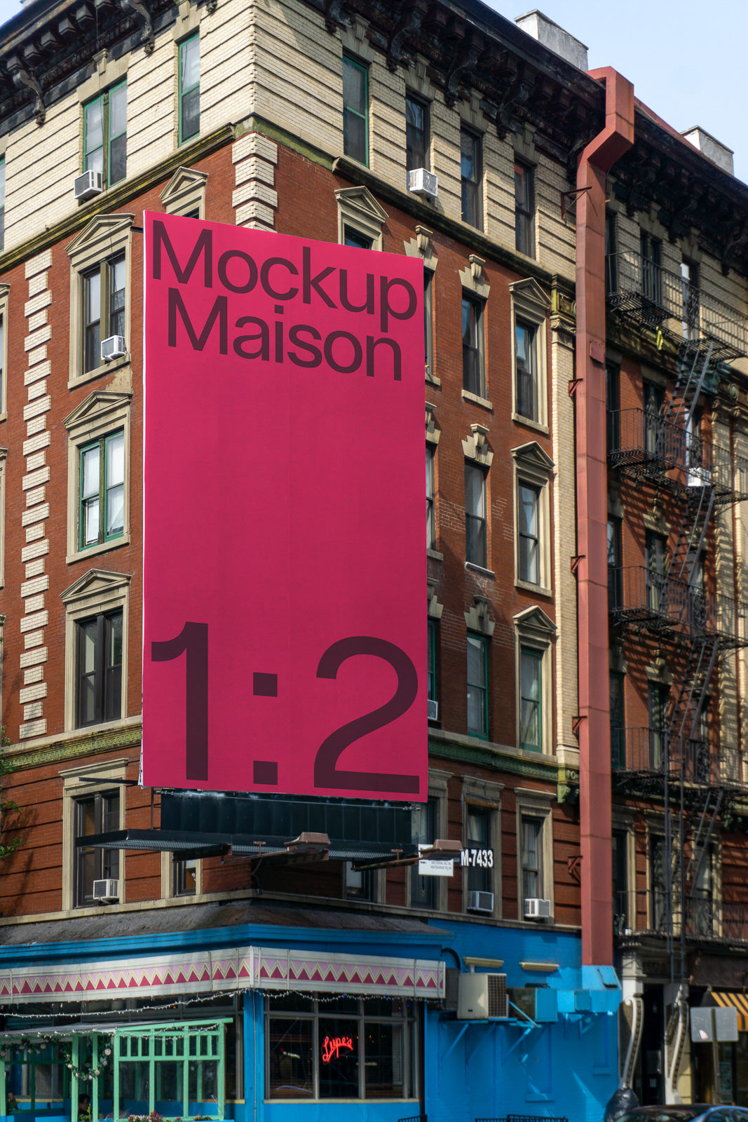PSD mockup of a large pink billboard with the text "Mockup Maison 1:2" on the side of a brick building in an urban setting.