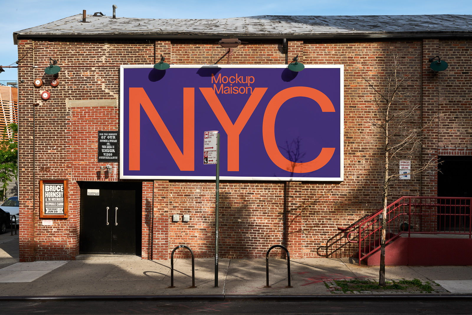 PSD mockup of large billboard on a red brick building facade, featuring bold orange "NYC" text on a purple background, with urban street elements.