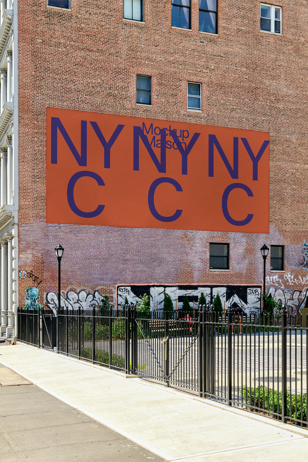 PSD mockup of a large brick wall with an orange backdrop displaying bold, blue letters "NY NY C C" above a fenced sidewalk and garden area.
