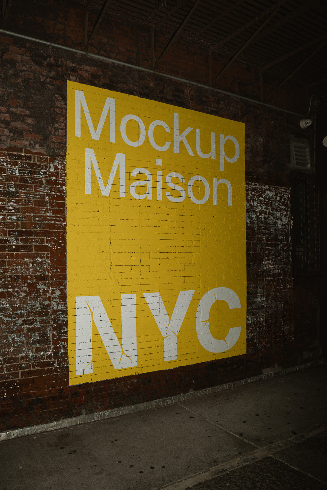 PSD mockup of a yellow wall mural with "Mockup Maison NYC" in white lettering on a brick wall, blending urban grit with bold typography.