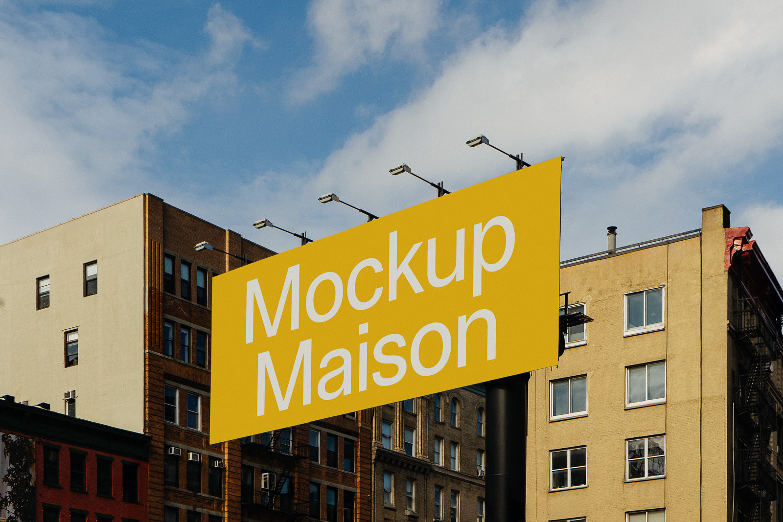 PSD mockup of a large yellow billboard with "Mockup Maison" text, set against an urban backdrop of buildings under a blue sky.