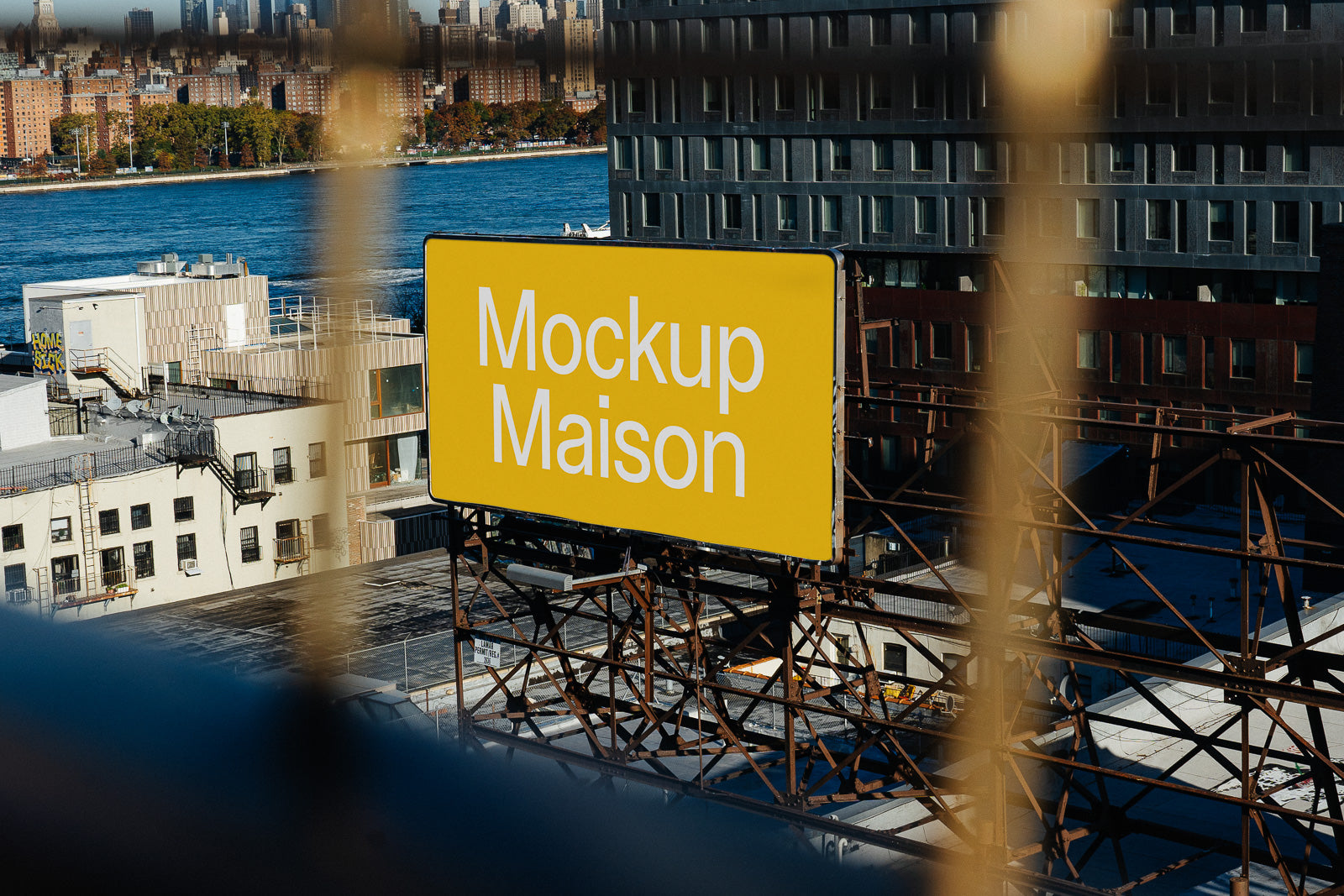 PSD mockup of a large yellow billboard with "Mockup Maison" text, set on a rooftop overlooking cityscape and river in the background.