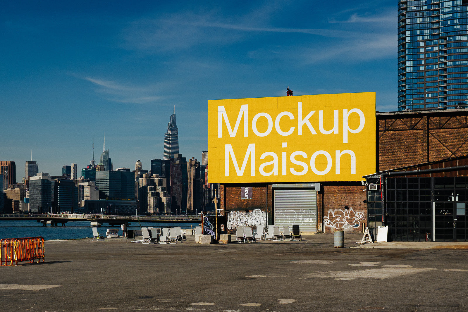 PSD mockup of a large yellow billboard on an industrial building with city skyline in the background, featuring bold white text reading "Mockup Maison."