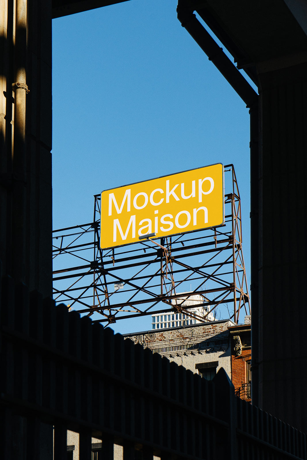 PSD mockup of a yellow billboard sign with "Mockup Maison" against a clear blue sky, framed by architectural elements.