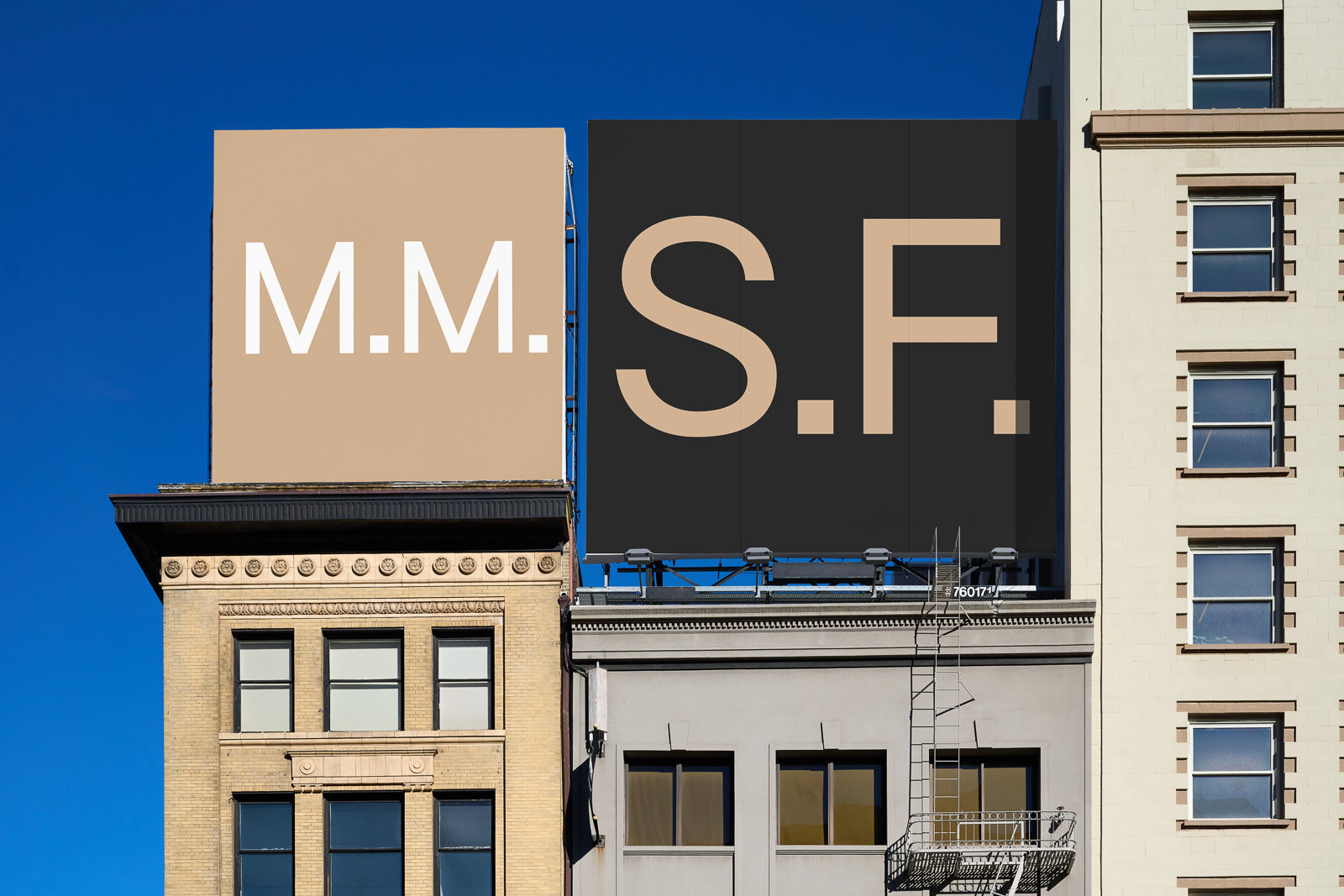 PSD mockup of two large billboards on a building against a clear blue sky, displaying the letters "M.M." and "S.F." in bold, contrasting colors.