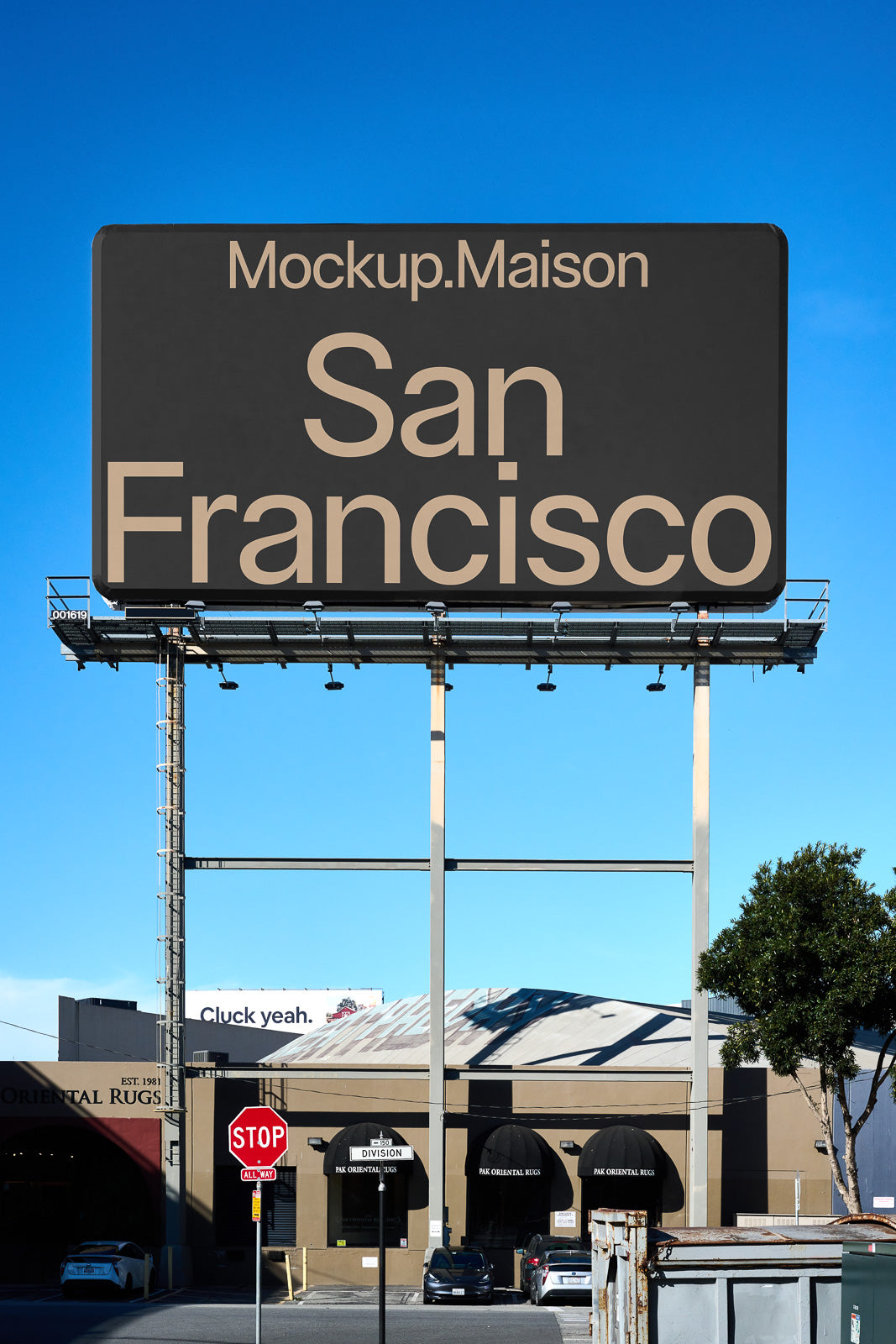 PSD mockup of a large billboard displaying "San Francisco" under a clear blue sky, with nearby industrial buildings and a stop sign in the foreground.