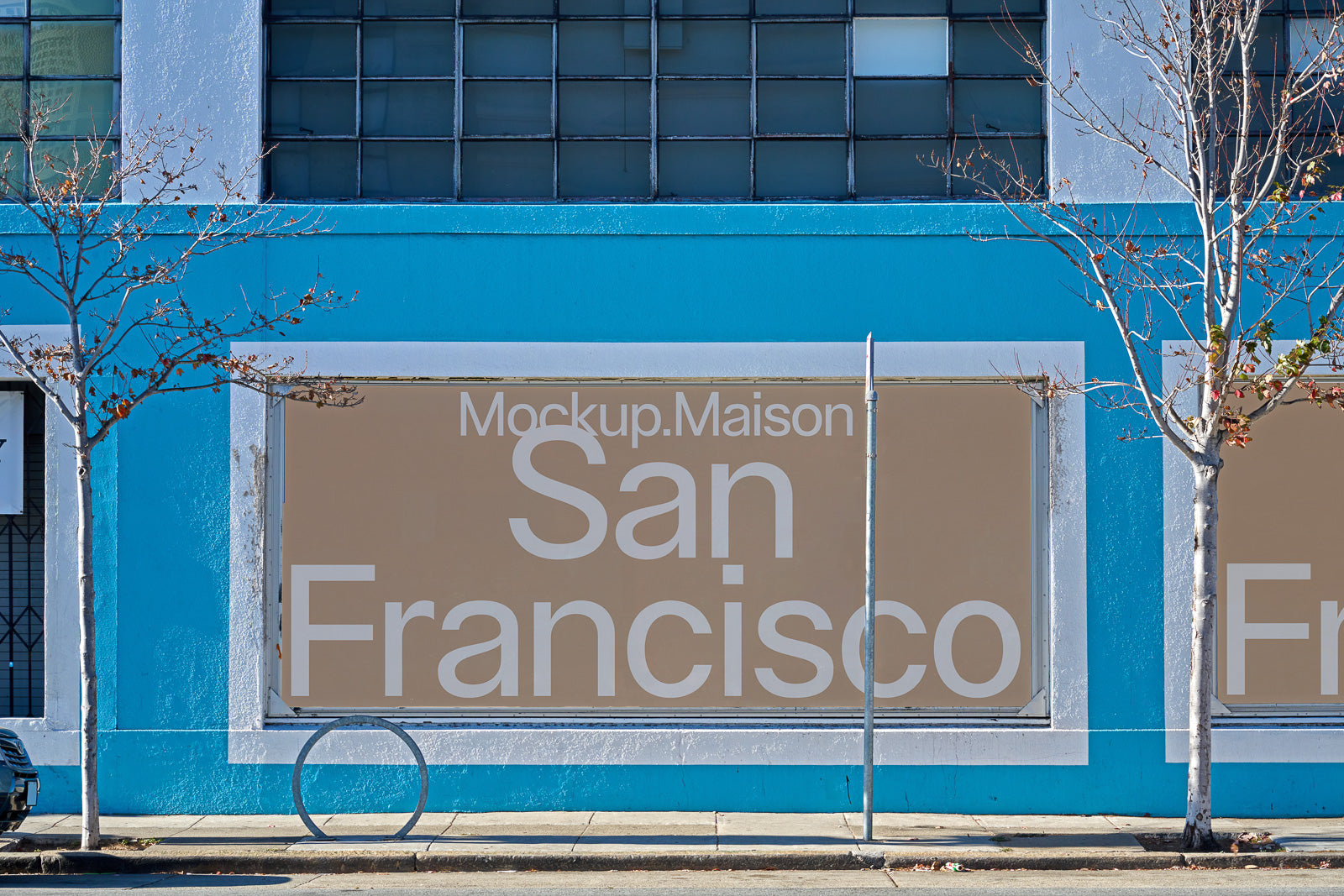 PSD mockup of a large outdoor billboard on a blue building facade with trees and windows, displaying "Mockup.Maison San Francisco."