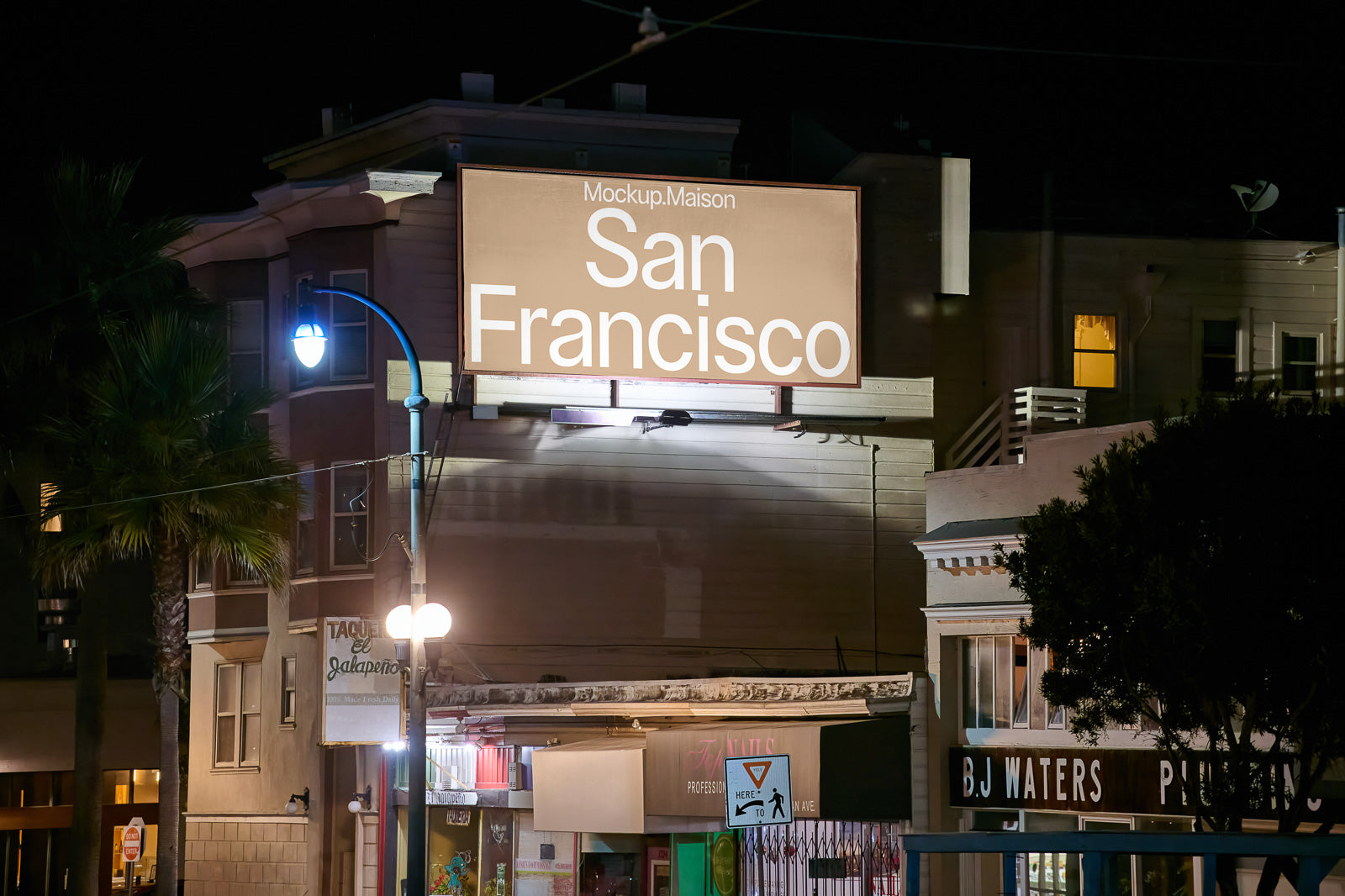 PSD mockup of an illuminated billboard at night displaying "San Francisco" in large white letters, placed against the backdrop of a city street with lit storefronts.