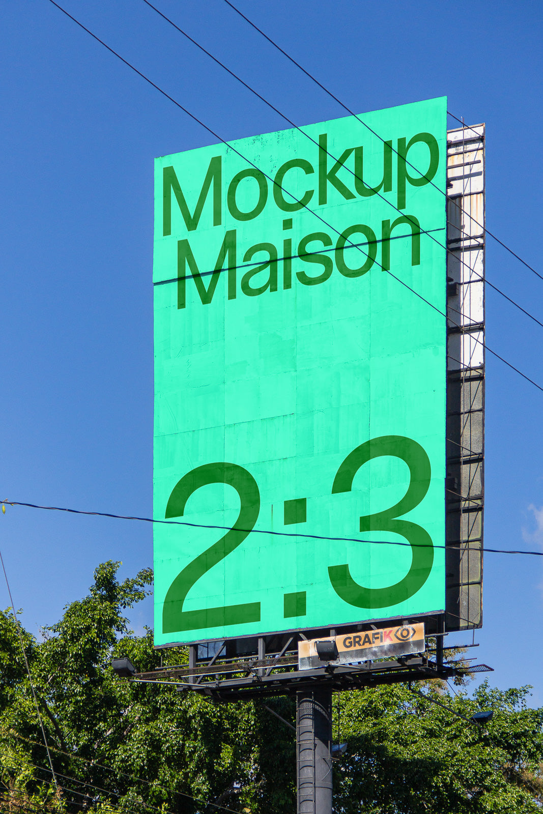 PSD mockup of a large outdoor billboard displaying "Mockup Maison" and "2:3" in bold text against a clear blue sky.