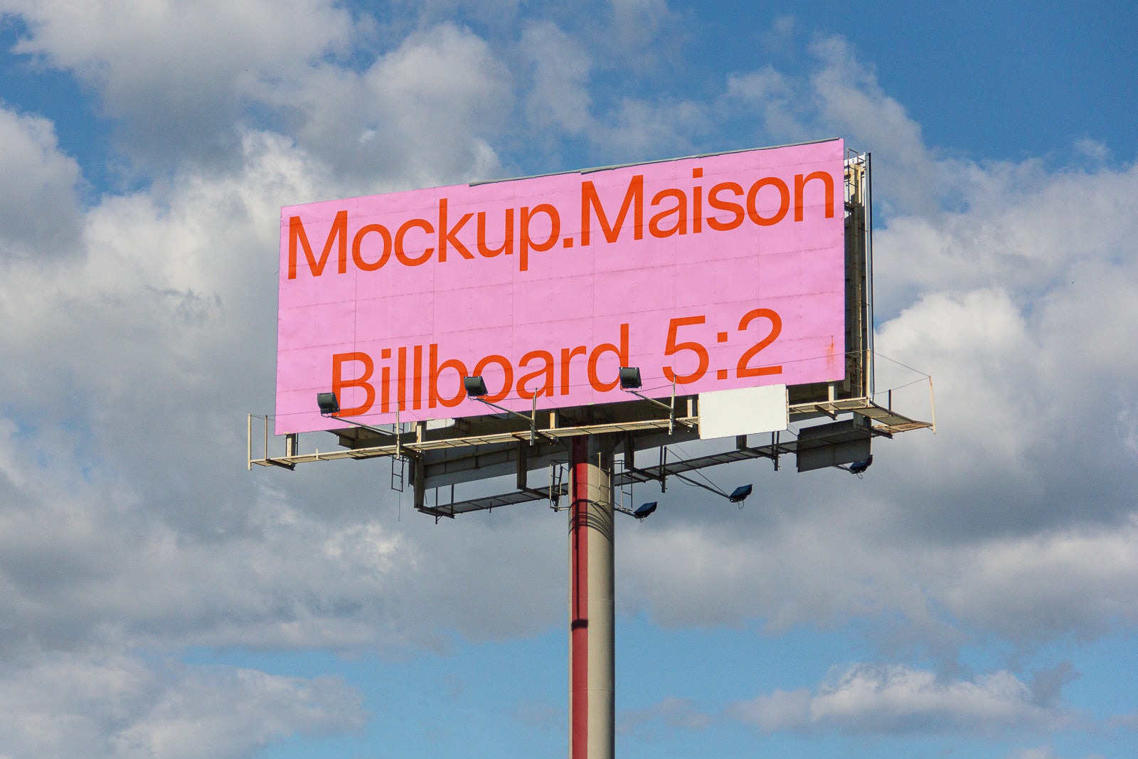PSD mockup of a large billboard against a cloudy sky, displaying "Mockup.Maison Billboard 5:2" in bold orange text on a pink background.