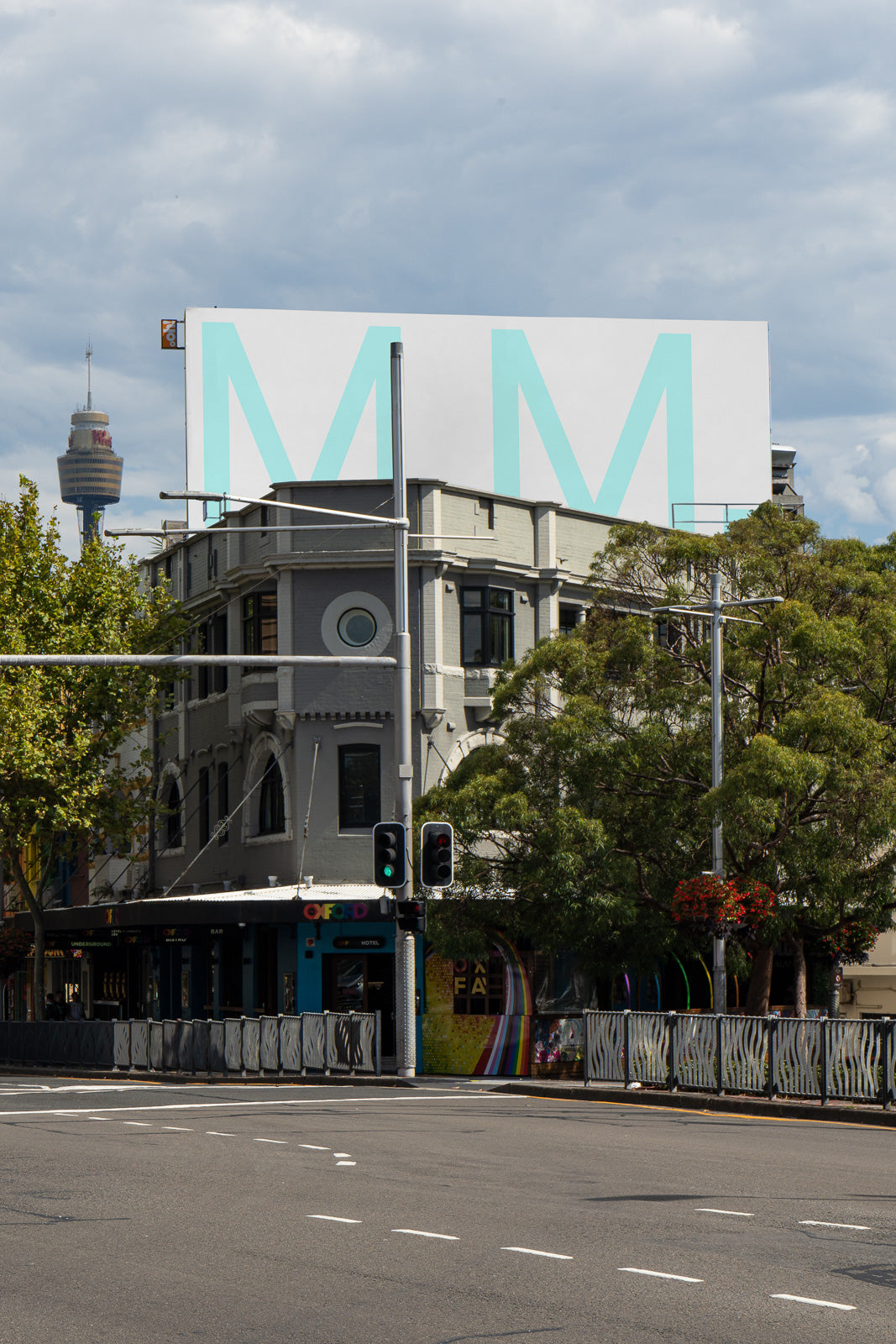 PSD mockup of a large city billboard above a historic building on a street corner, with a distant tower visible in the background.