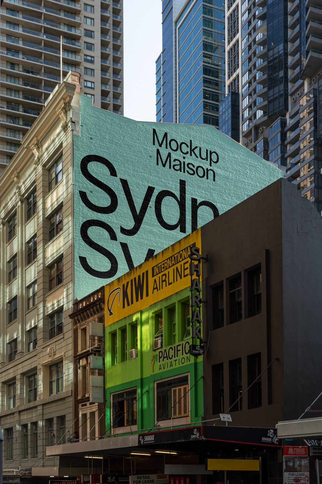 PSD mockup of a city building with large billboard text "Mockup Maison Sydn". Surrounding modern skyscrapers create an urban backdrop.