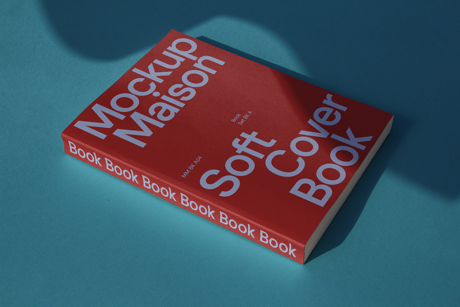 PSD mockup of a red softcover book lying on a blue surface, titled "Mockup Maison Soft Cover Book" with text along the spine.