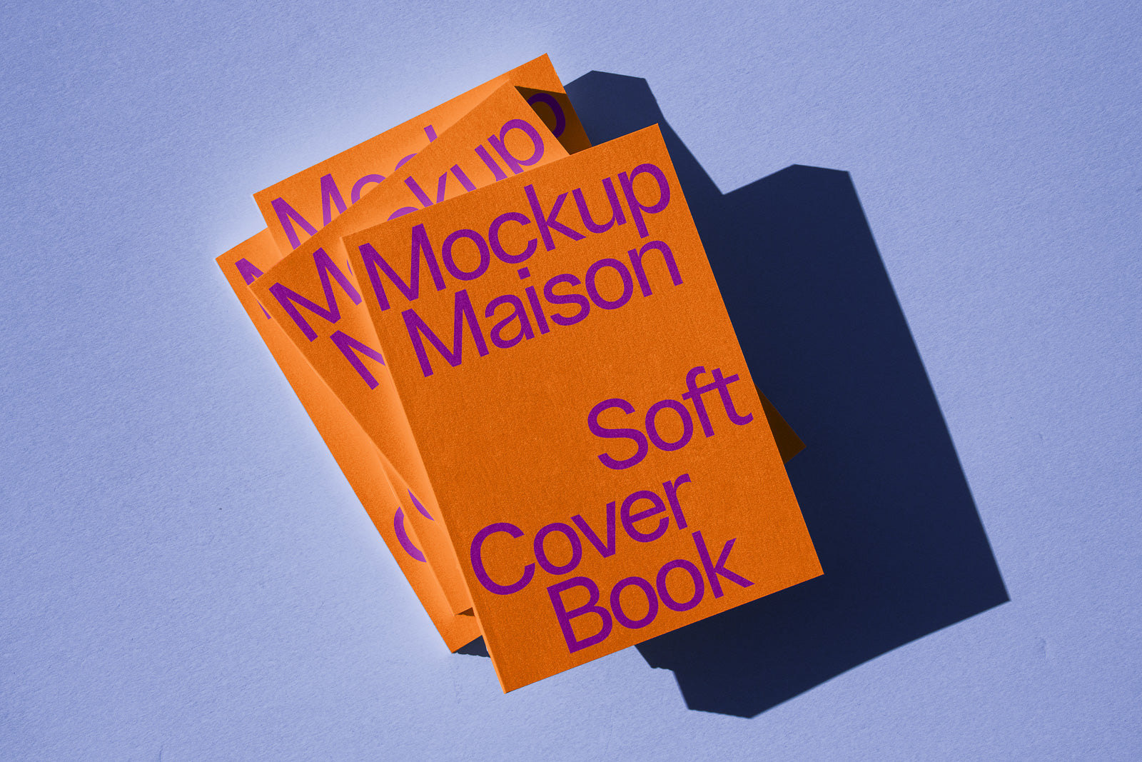 PSD mockup of an orange softcover book stack with purple text on a light blue surface, creating bold shadows.