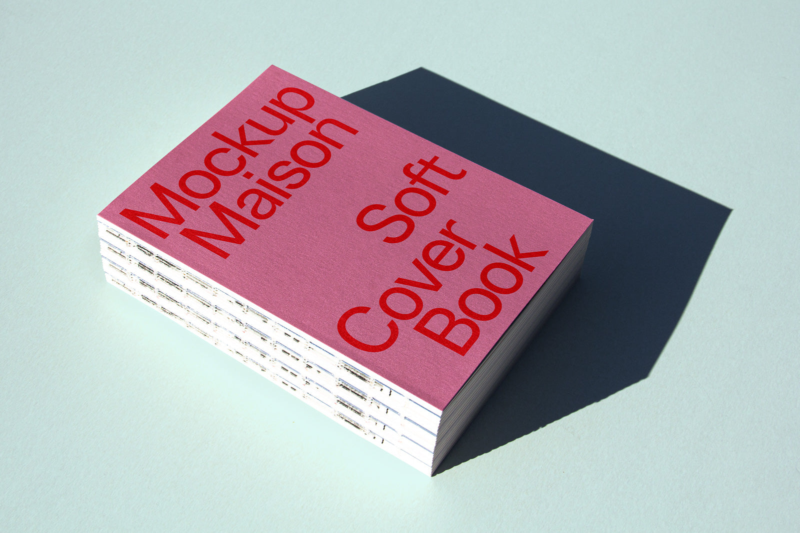 PSD mockup of a stack of soft cover books with a pink cover and bold red text on a light blue background casting a shadow.
