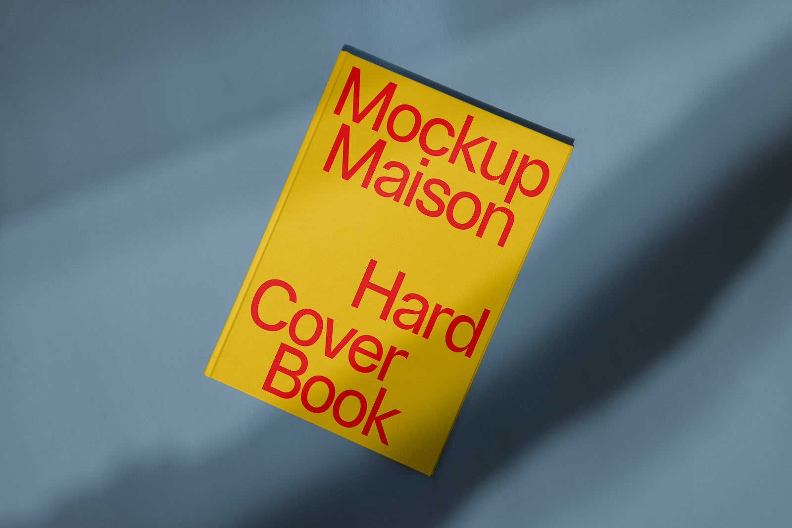 PSD mockup of a yellow hardcover book with red text, titled "Mockup Maison Hard Cover Book," set against a soft blue background.