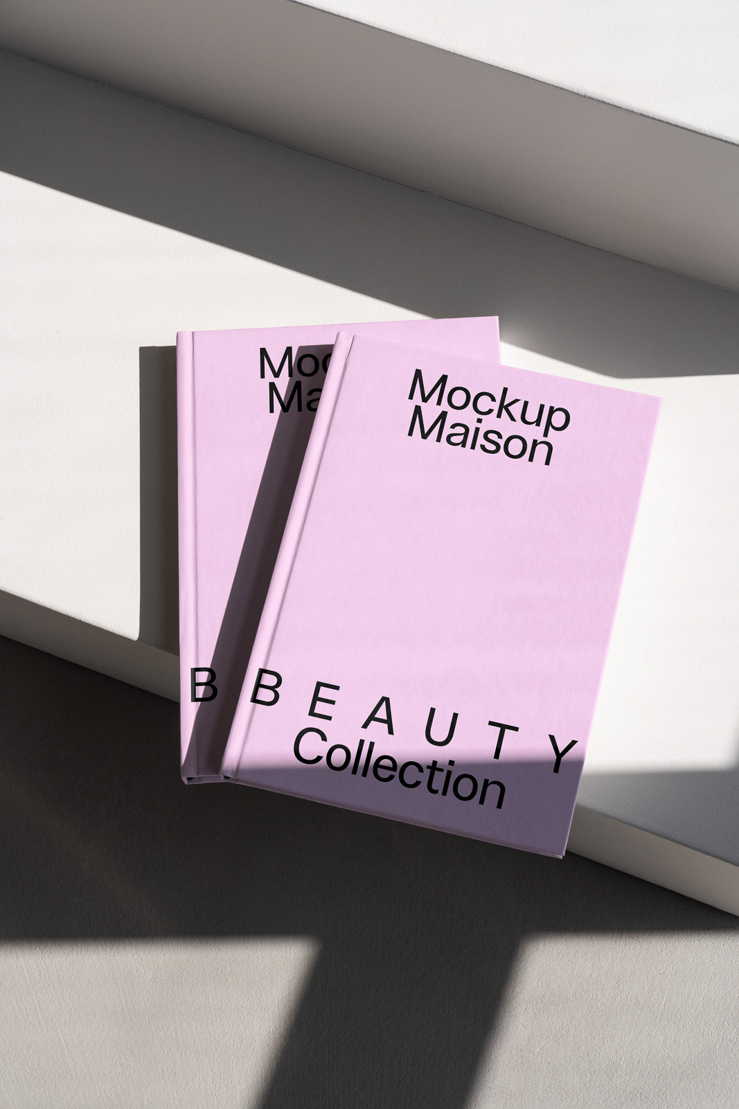 PSD mockup of two pink hardcover books titled "Mockup Maison Beauty Collection" placed on a white surface with soft shadows.