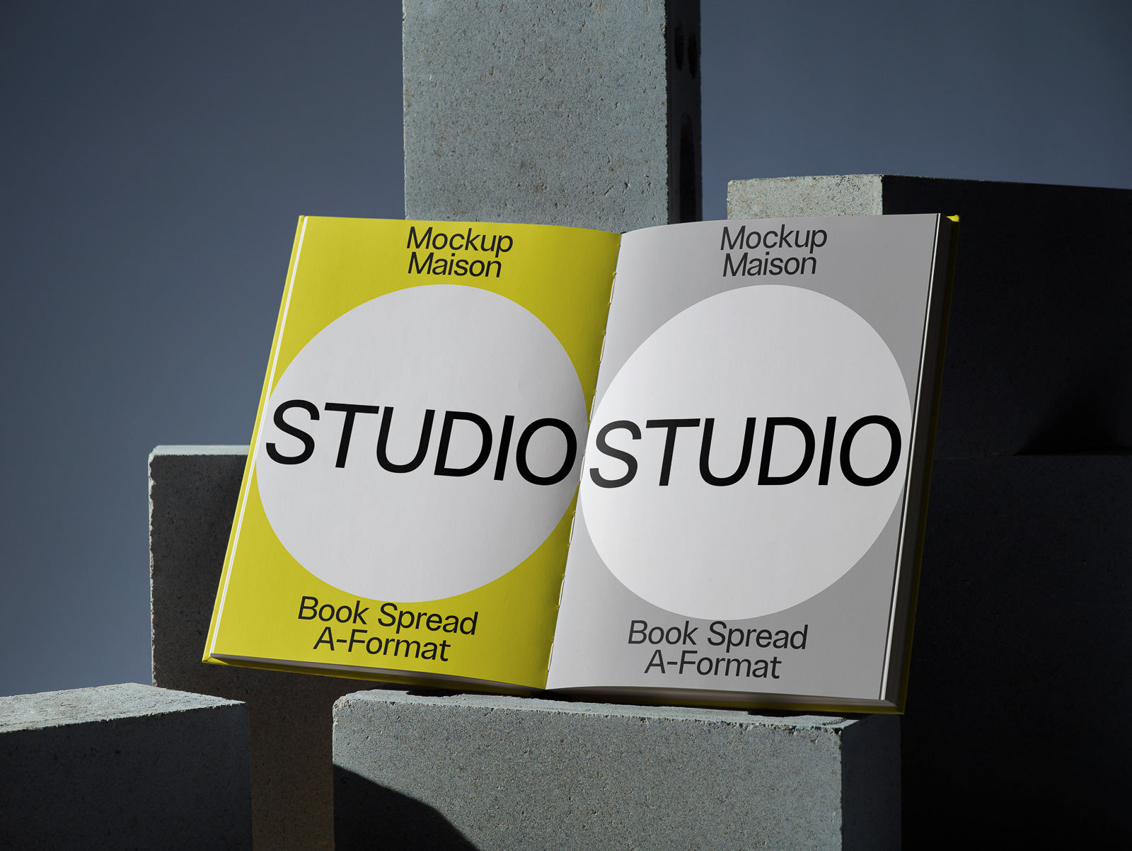 PSD mockup of an open book displaying yellow and gray pages with "STUDIO" text, placed on concrete blocks, emphasizing modern design elements.