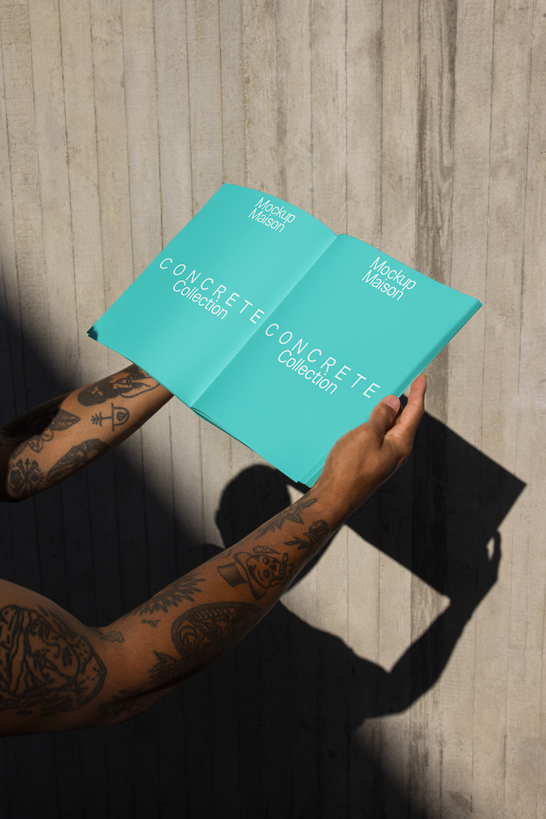 PSD mockup of a person holding an opened turquoise booklet against a concrete wall, displaying the text "Concrete Collection."