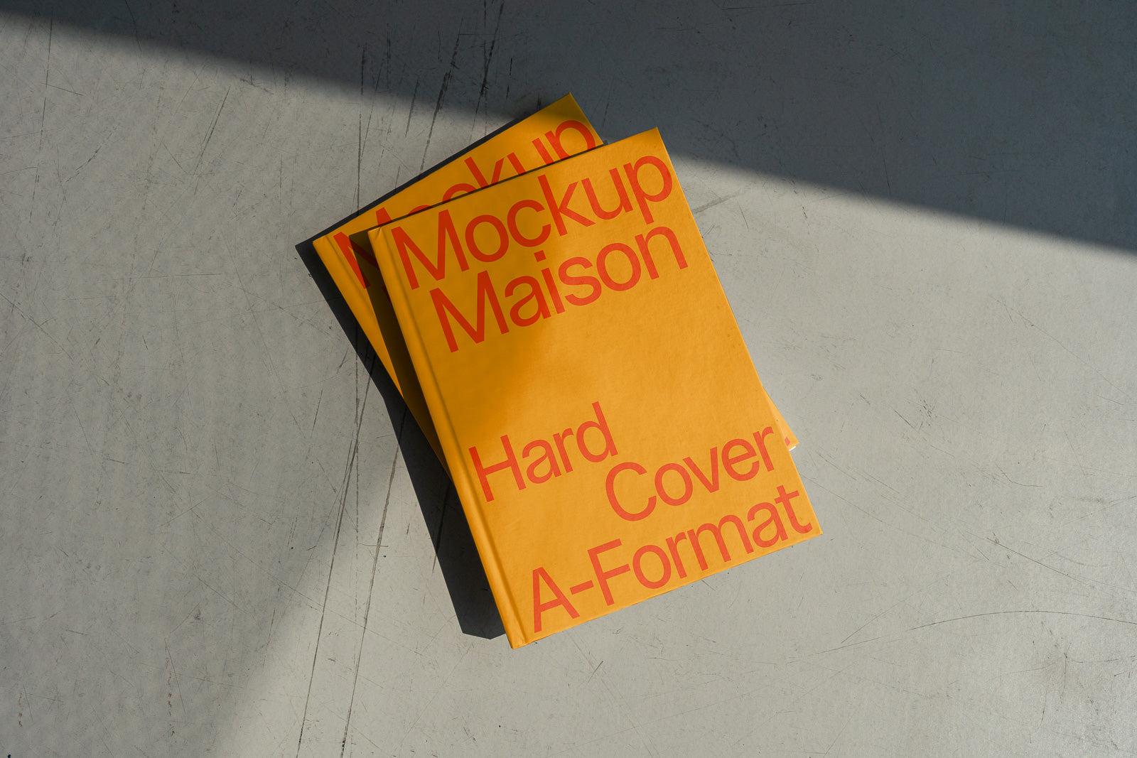 PSD mockup of a hardcover book with a yellow cover and bold red text, placed on a textured gray surface with soft shadows.