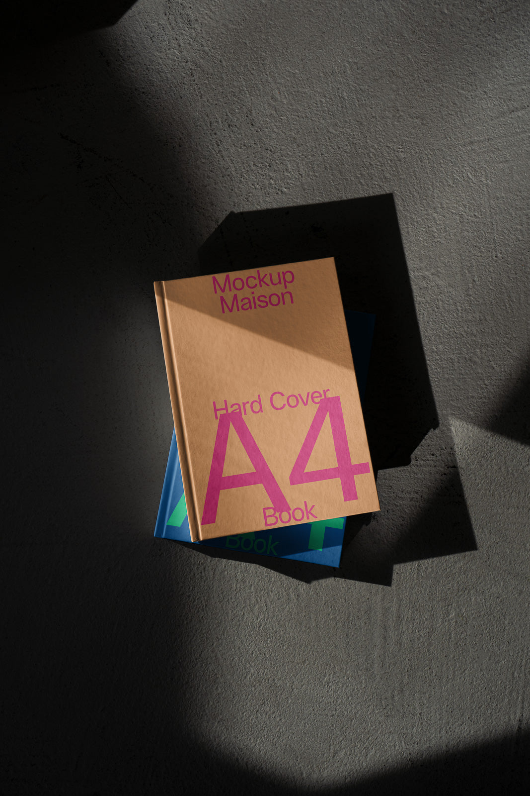 PSD mockup of an A4 hardcover book with "Mockup Maison" and colorful cover design on a textured surface, casting shadows.