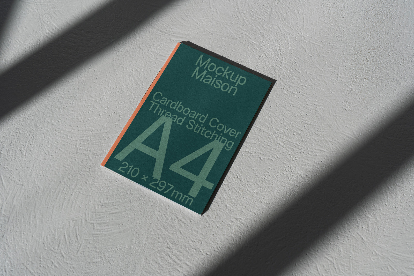 PSD mockup of an A4-sized green cardboard cover with thread stitching, featuring dimensions 210x297mm, lying on a textured surface with shadows.