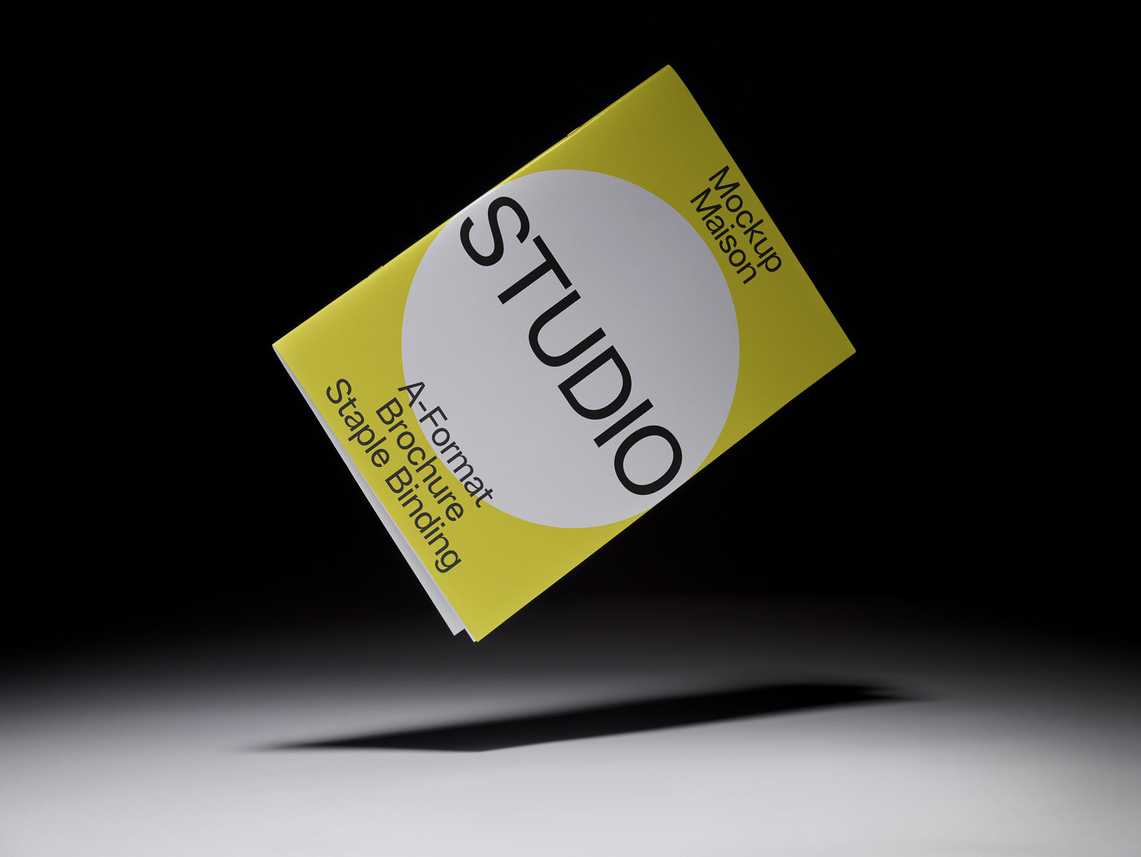 PSD mockup of a floating, yellow, A-format brochure with staple binding against a dark background, featuring the word "STUDIO" prominently.