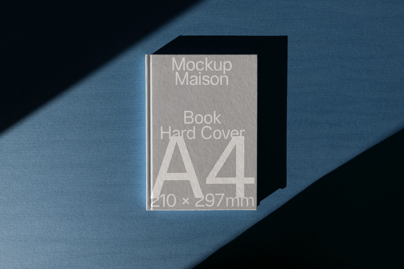 PSD mockup of a hard cover A4 book with shadow on a blue surface, featuring text "Mockup Maison Book Hard Cover" and dimensions 210 × 297 mm.