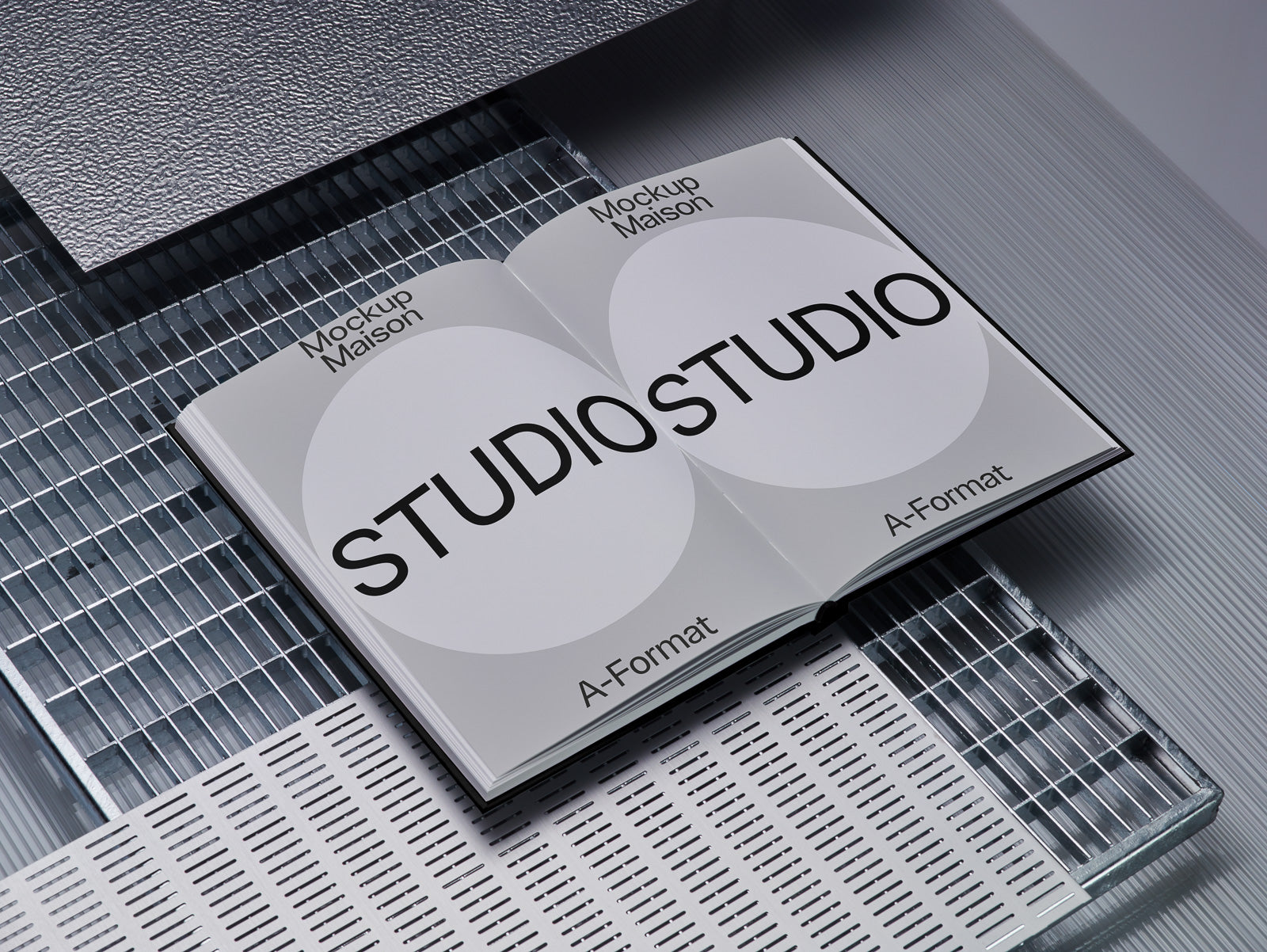 PSD mockup of an open booklet displaying "Studio" text in bold black font, set on a metallic and textured surface background for visual contrast.
