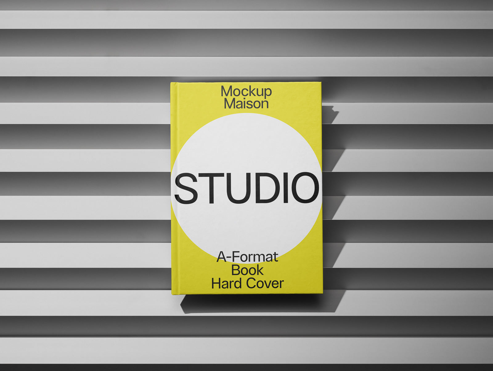 PSD mockup of a yellow hardcover book titled "Studio" resting on a gray, textured background with horizontal lines, featuring bold typography on the cover.