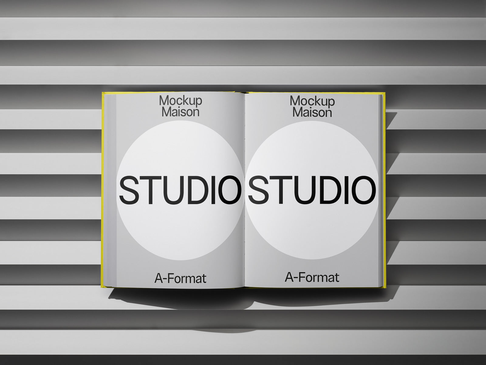 PSD mockup of an open book with "Studio" text on both pages, resting on a striped grey surface.