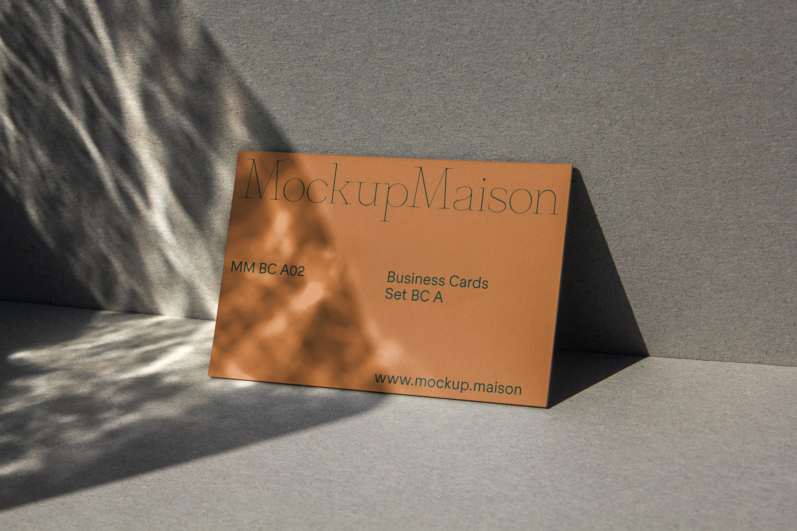 PSD mockup of a brown business card displaying "MockupMaison" text, shadowed against a textured surface, showcasing card details and website.